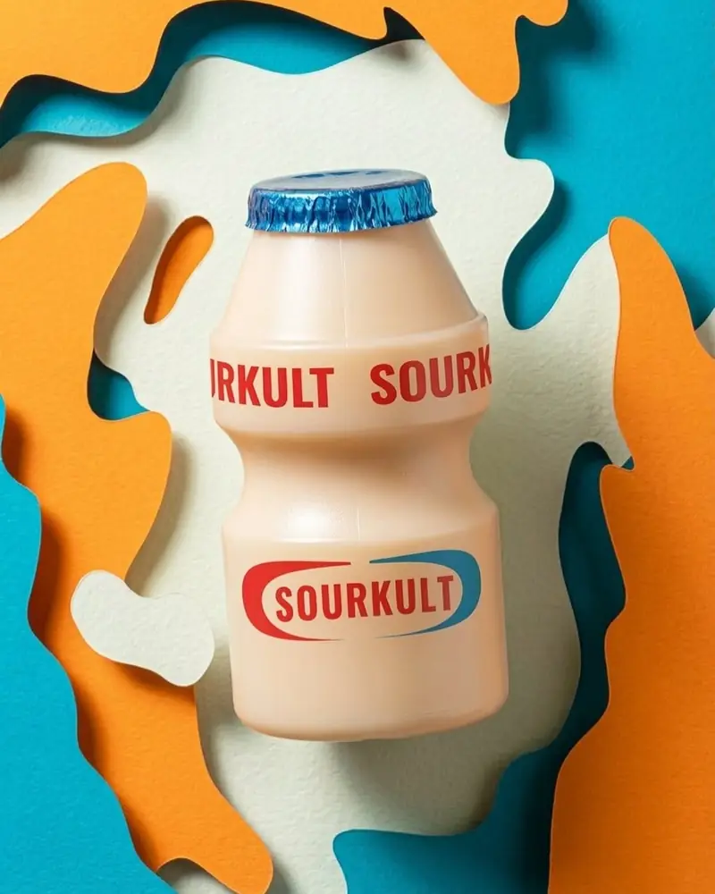 Sourkult yoghurt-drink can against layered paper-cut artwork