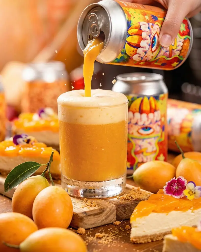 Golden sour poured from a patterned can beside cheesecake